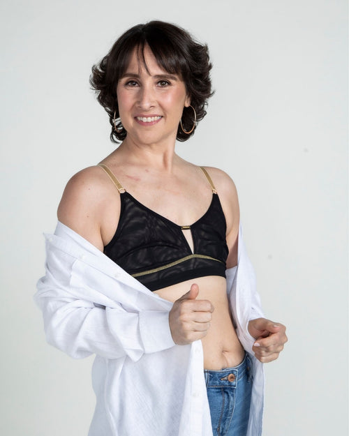 Black / Implants & model wearing the Victoria Pocketed Keyhole bralette with gold lace trim and gold jewel that says anaono