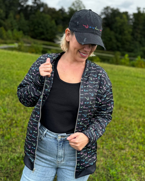 Multi & breast cancer survivor wearing the limited edition metastatic breast cancer awareness bomber jacket front view with the jacket open